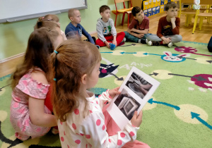 Dzieci oglądają zdjęcia, przedstawiające powstawanie glinianych przedmiotów.