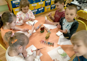 Dzieci ozdabiają gliniane wazoniki.