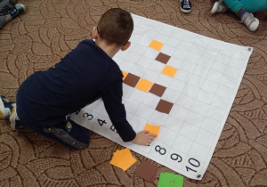chłopiec kładzie kwadrat na określonym polu 4