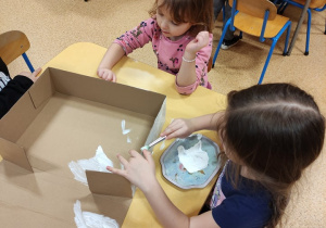 Dziewczynki malują pudełko.
