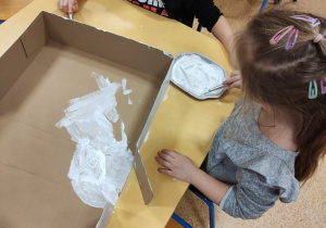 Dzieci malują pudełko.