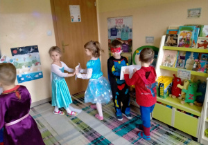Dzieci tańczą w parach z kartką między dłońmi.