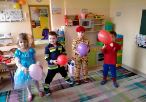 Dzieci tańczą w kole z balonami w rękach.