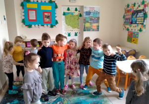 Dzieci tańczą wspólnie trzymając się za ramiona.