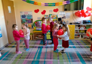 Dzieci tańczą w parach, trzymając serduszkowy balon miedzy brzuchami