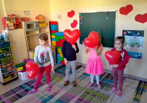 Dzieci stoją i trzymają w ręku serduszkowy balon.
