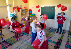 Dzieci tańczą i podrzucają balony nad głową.