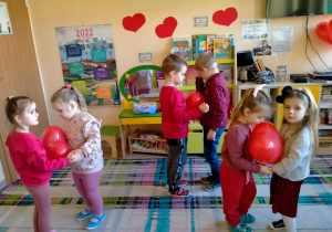 Dzieci tańczą w parach z serduszkowym balonem między brzuchami.