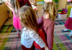 Dziewczynki tańczą w parach z serduszkowym balonem między plecami.