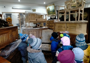 Dzieci oglądają różne rodzaje zegarów i starodawne meble.