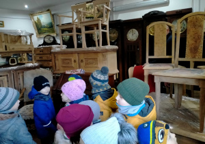 Dzieci oglądają różne rodzaje zegarów i starodawne meble.