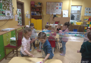 Dzieci malują paluszkami na folii spożywczej.